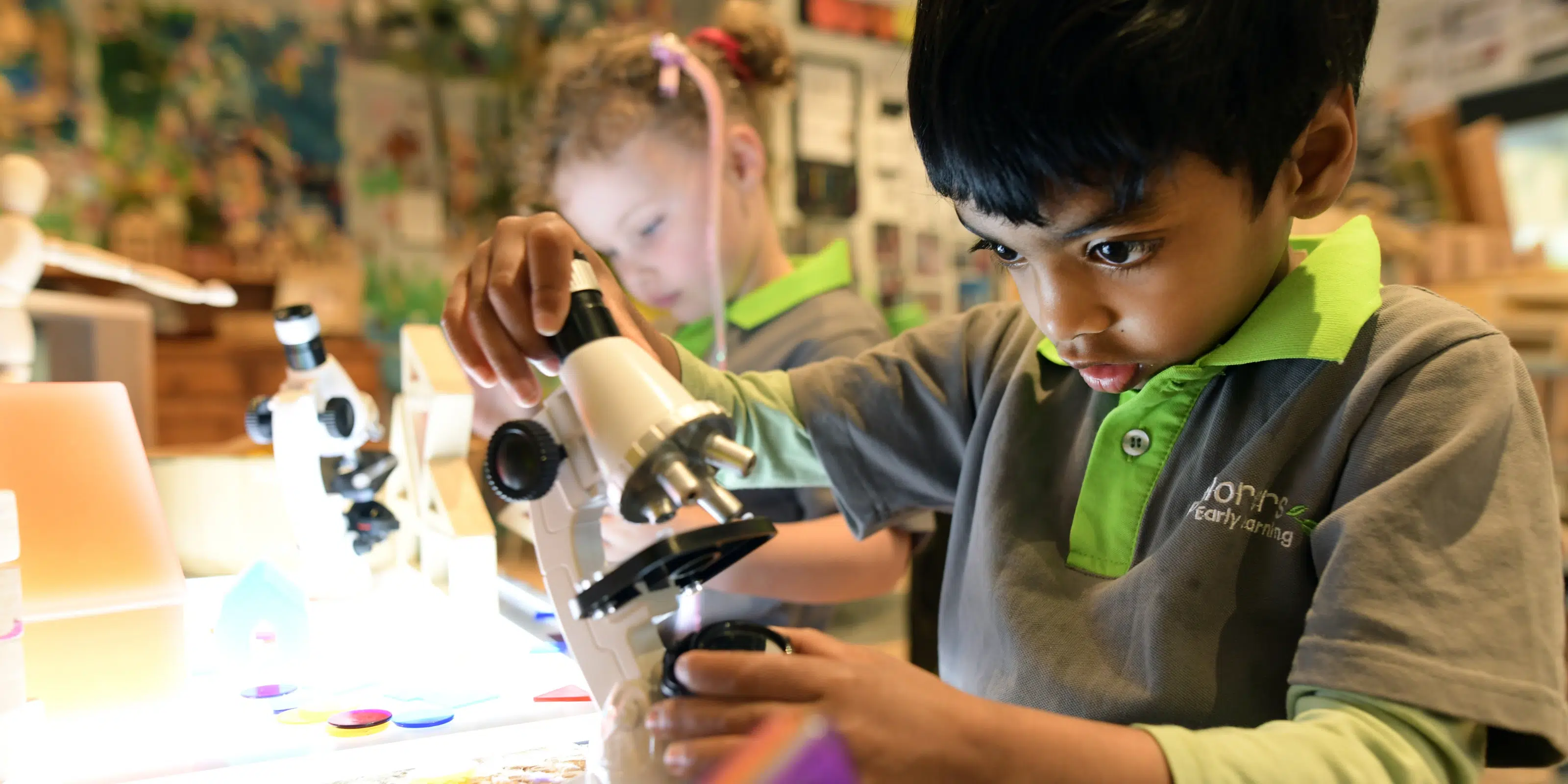Child using a microscope at Explorers Early Learning