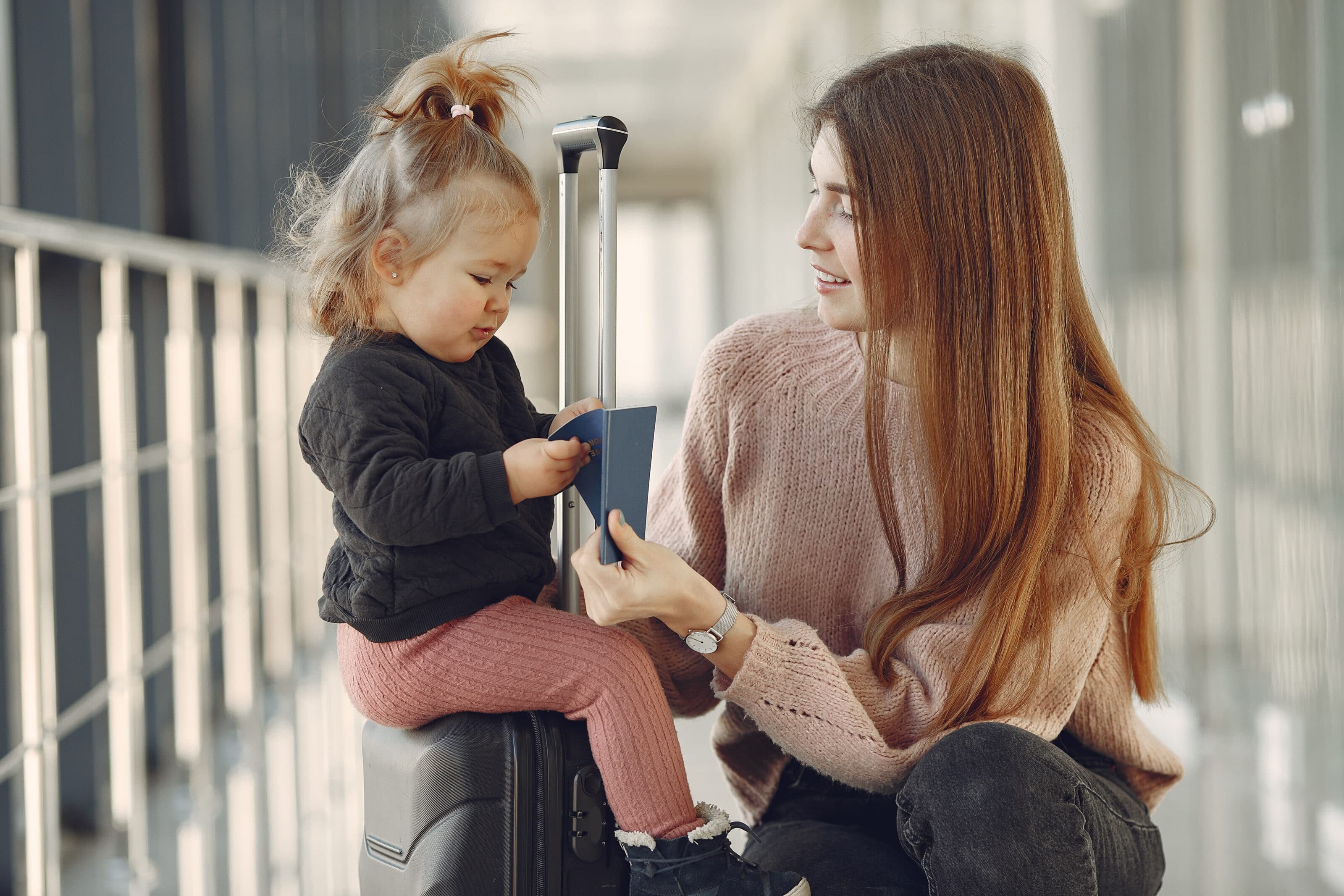 Mother with daughter at the airport, suitcase in hand