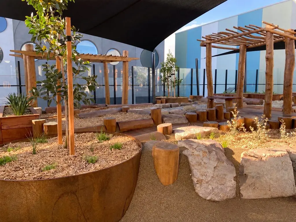 The Armstrong Creek outdoor play space, with timber posts, rocks and planted garden beds