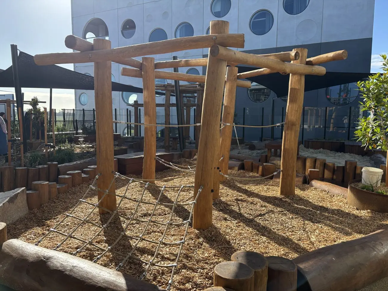The timber climbing structure and its rope net from another angle, with the sandpit behind